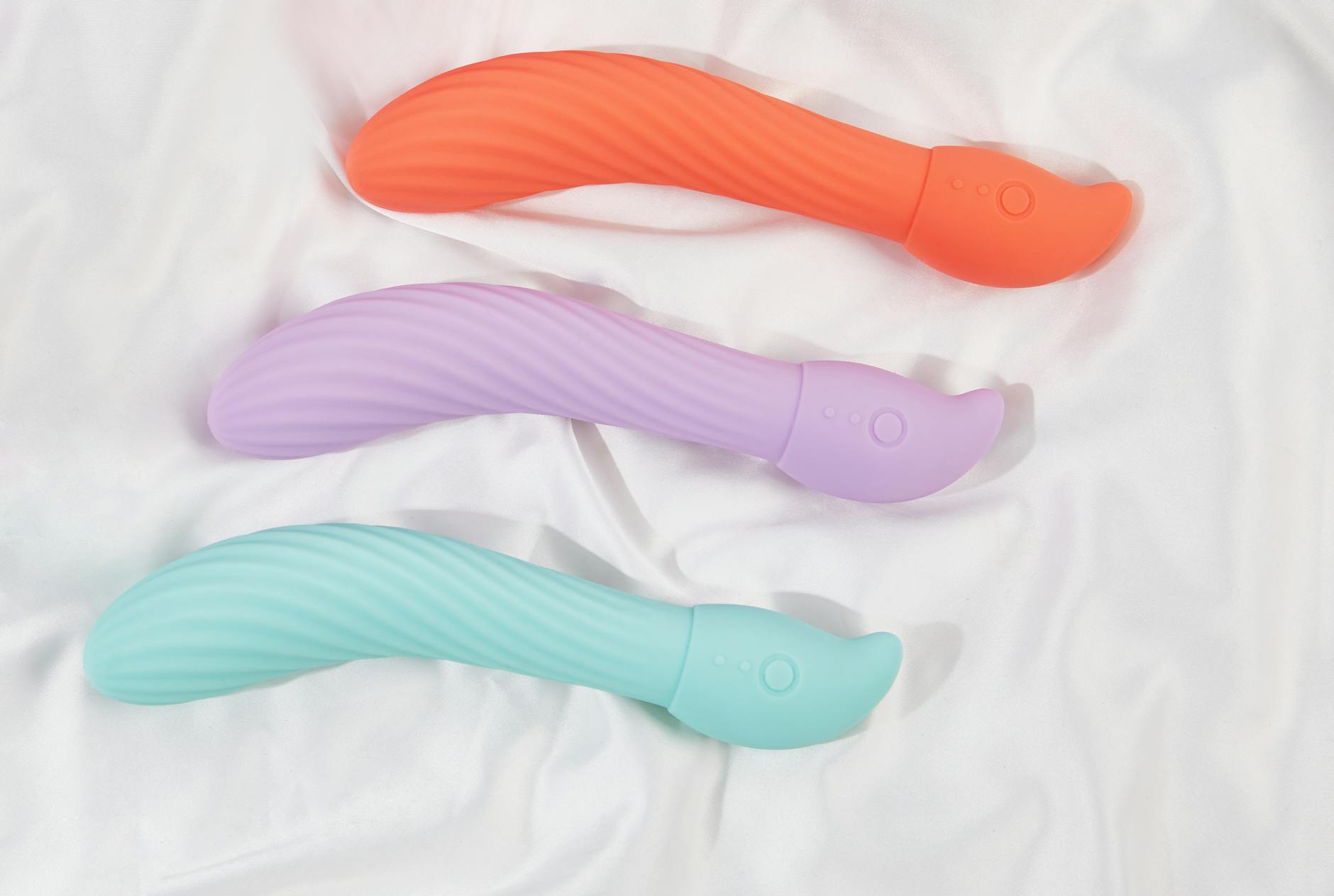 Diverse collection of colorful clitoral vibrators arranged on a black surface