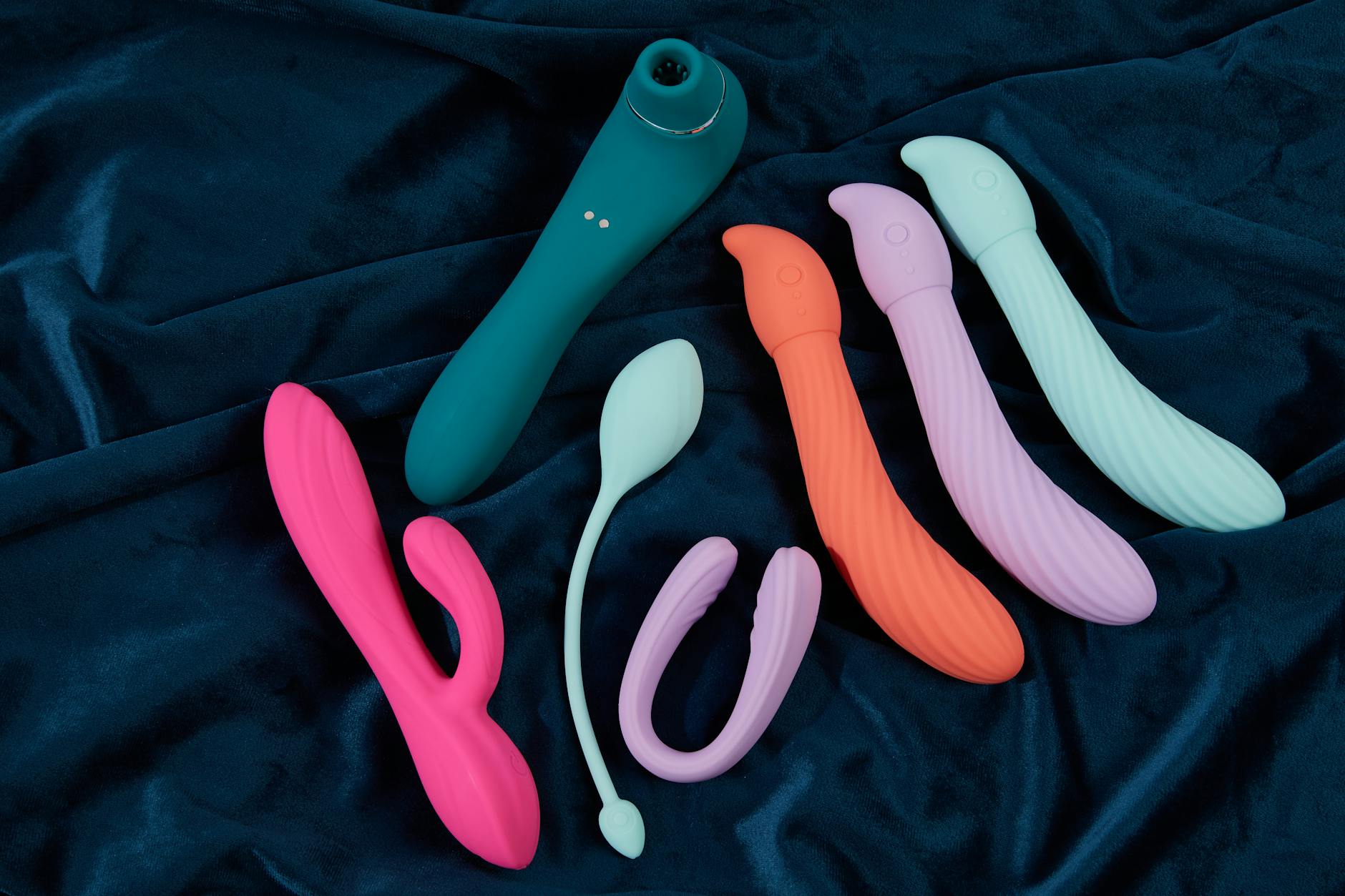 Woman holding silicone clitoral vibrators in thoughtful contemplation