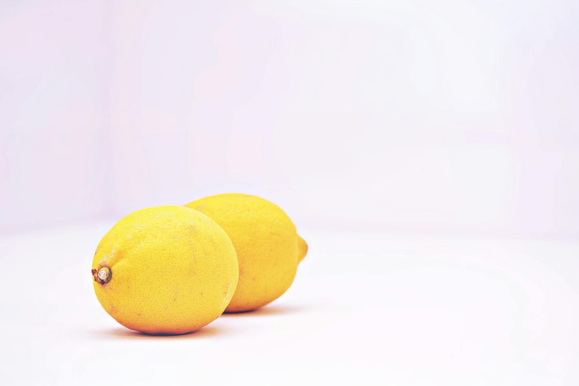 A woman holding a fresh lemon at a dining table, symbol of starting fresh