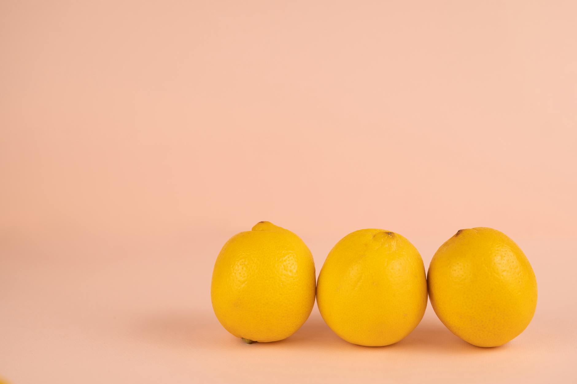 Bright yellow lemons arranged on pastel background, representing lemon vibrators and fresh pleasure